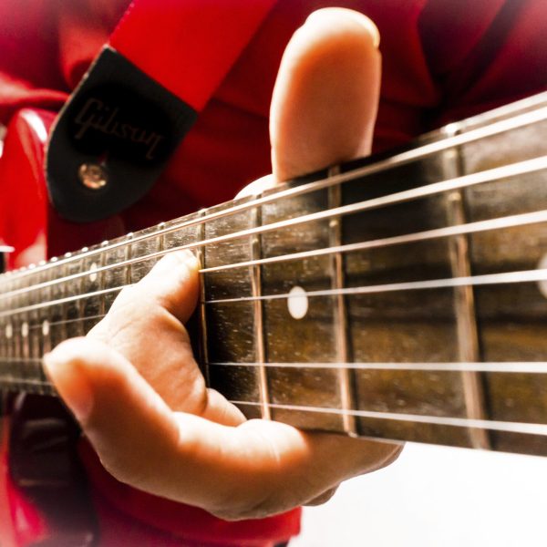Musician playing a chord on an electric les paul guitar.